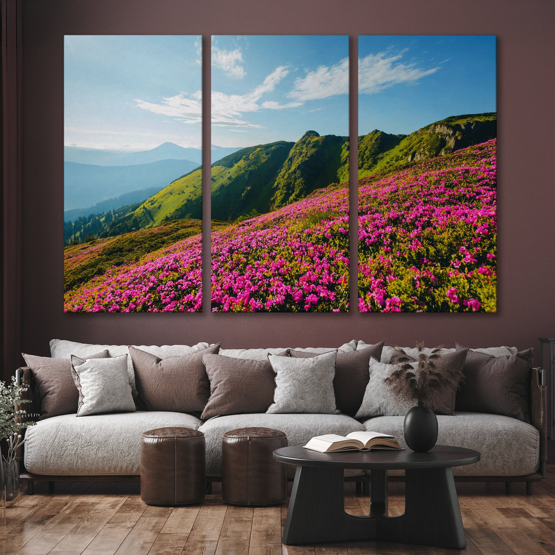 Canvas Print of a vibrant mountain landscape with pink flowers, green hills, and blue sky. Nature-inspired wall art in a modern living room.