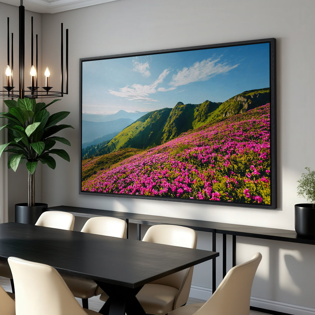 Framed Wall Art featuring a vibrant mountain landscape with pink flowers and green hills. Nature-inspired artwork with a blue, green, and pink color palette.