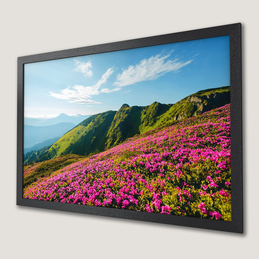 Framed Poster of vibrant mountain landscape with pink flowers, green hills, and blue sky. A beautiful nature-inspired print.