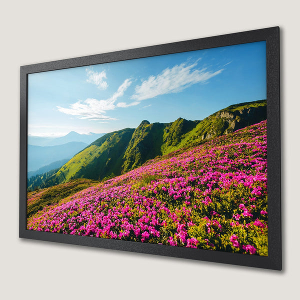 Framed Poster of vibrant mountain landscape with pink flowers, green hills, and blue sky. A beautiful nature-inspired print.