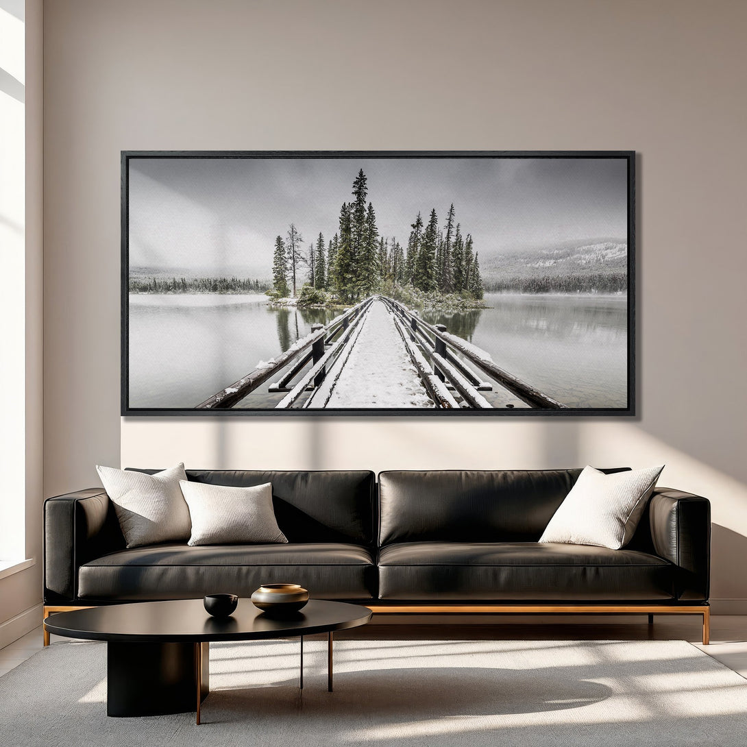 Framed Wall Art: Serene winter landscape Canvas Print featuring a snow-covered bridge and trees. Neutral color palette, perfect for adding a touch of nature to your home.