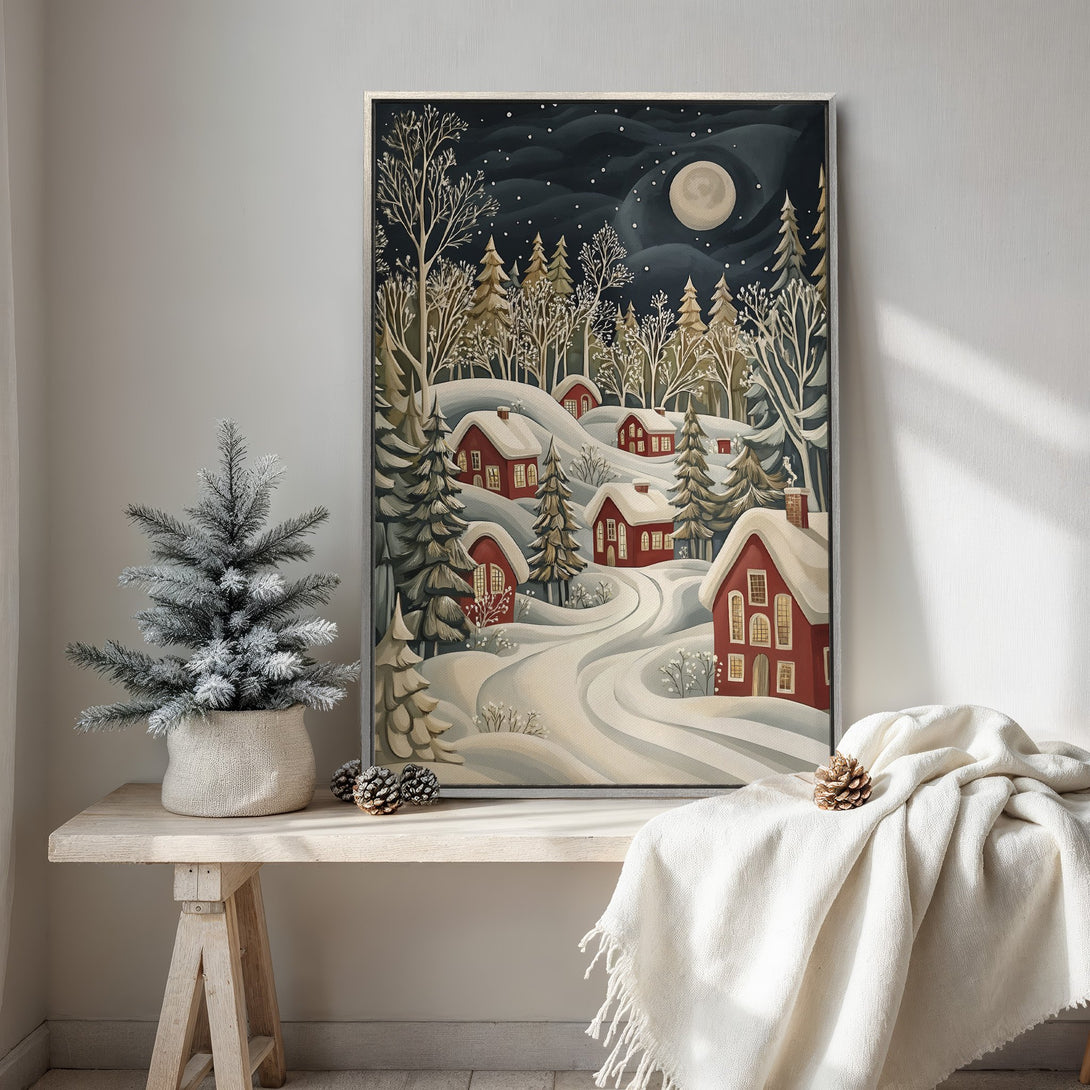 Framed Wall Art featuring a winter village scene. Charming illustration in a muted, cool color palette with red houses and snowy landscape. Perfect for cozy decor.