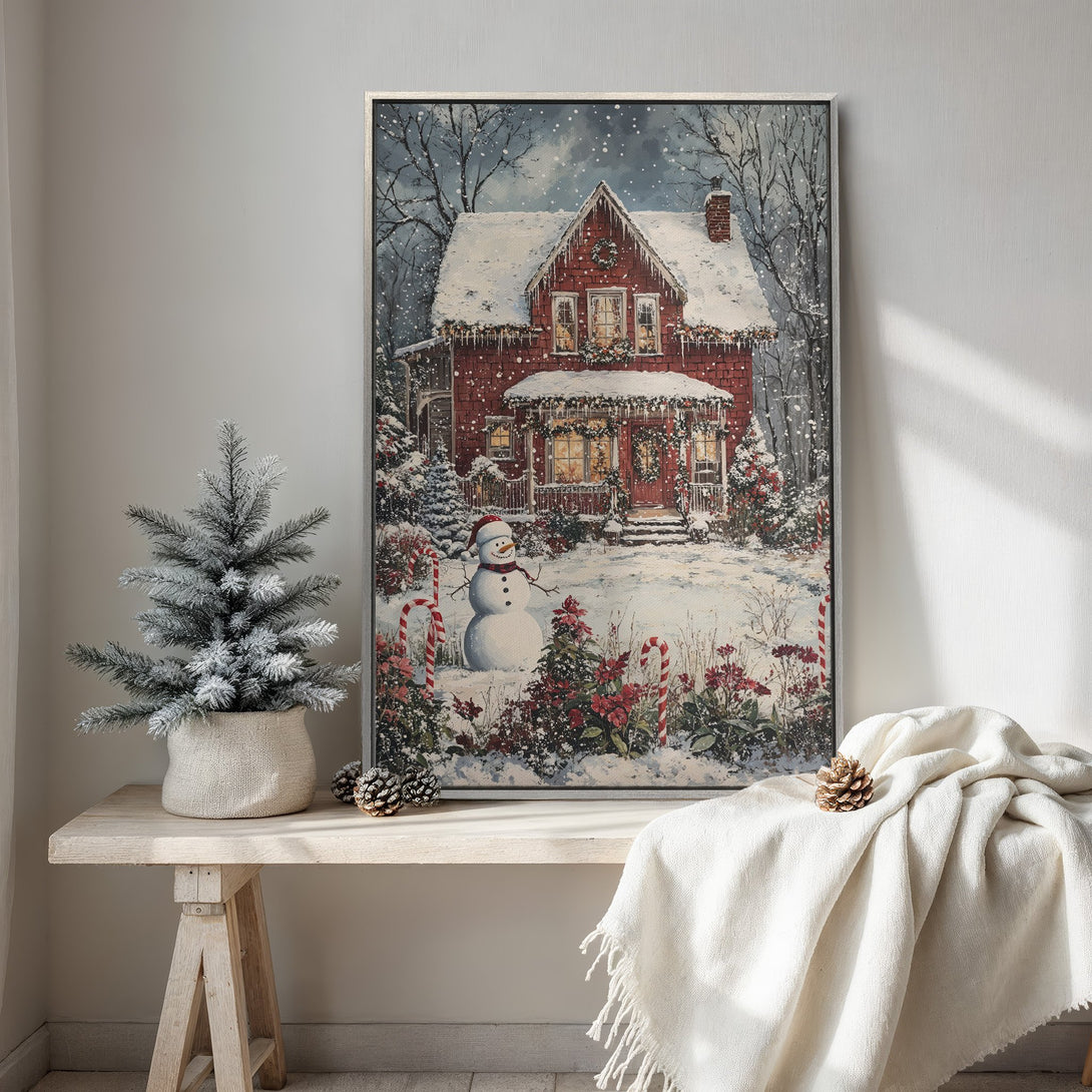 Framed Wall Art: Cozy winter scene Canvas Print of a snow-covered red house with a snowman. Warm, inviting colors perfect for holiday decor.