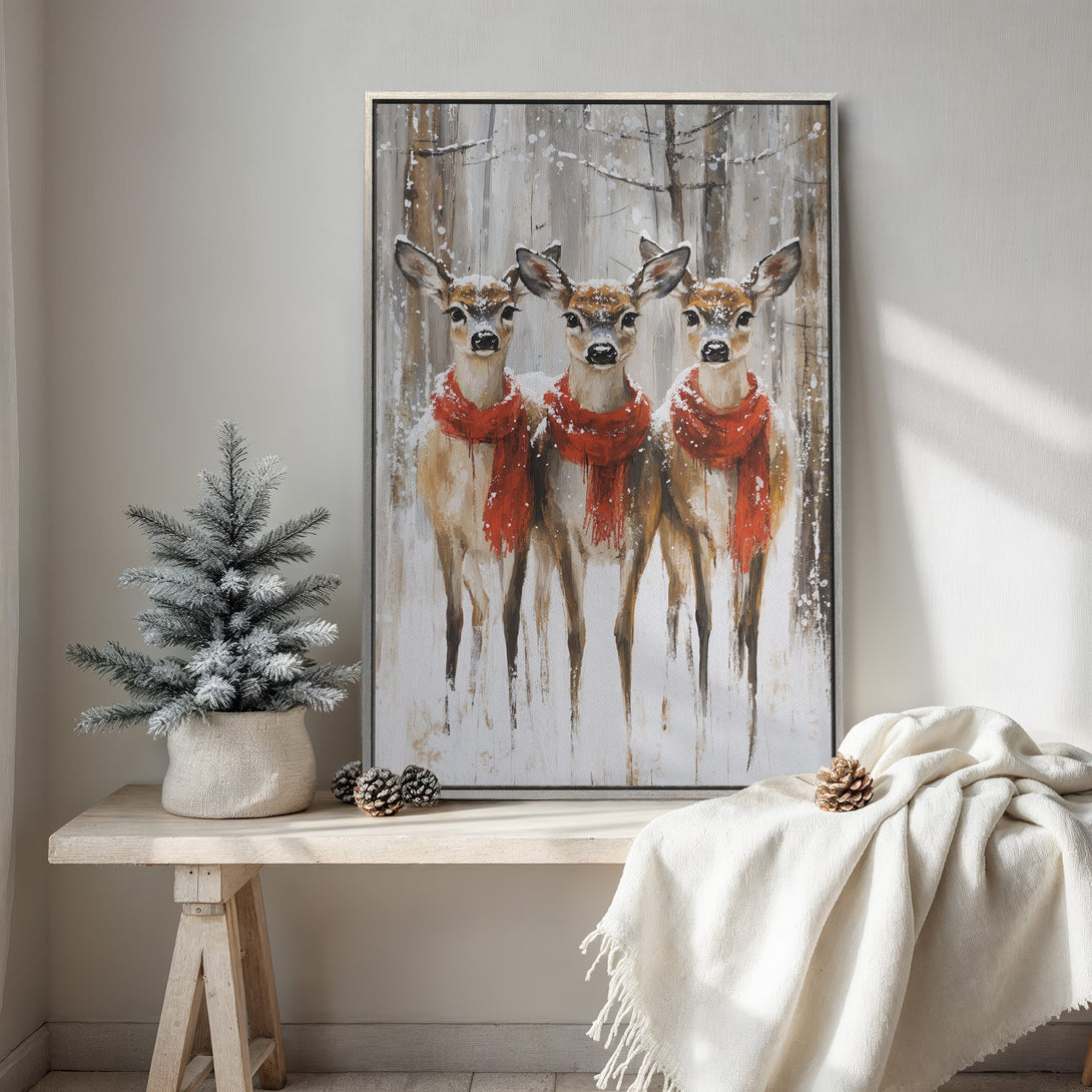 Framed Wall Art featuring three deer in a snowy forest scene, with red scarves. Rustic style, neutral and warm color palette. Perfect winter decor.