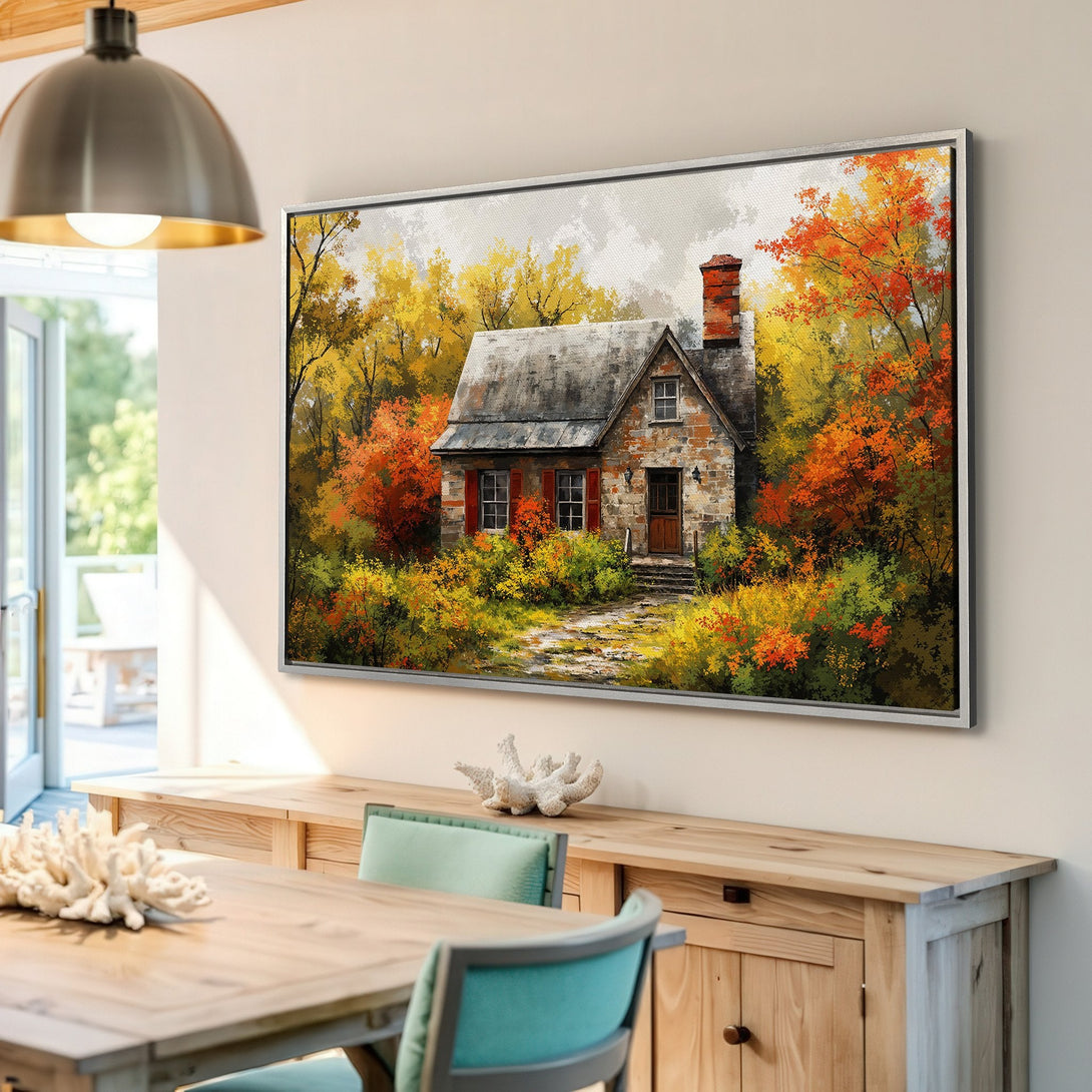 Framed Wall Art depicting a cozy cottage in an autumn landscape. Warm color palette of reds, oranges, and yellows. Perfect for adding a touch of nature.