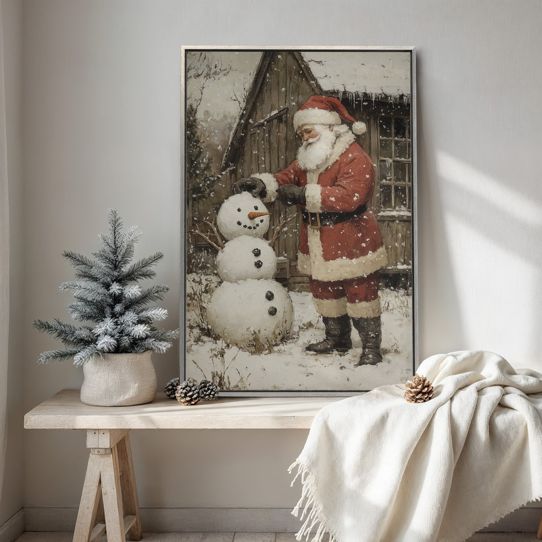 Framed Wall Art: Vintage painting of Santa Claus building a snowman in a snowy scene. Warm red & brown tones create a cozy, festive holiday vibe.