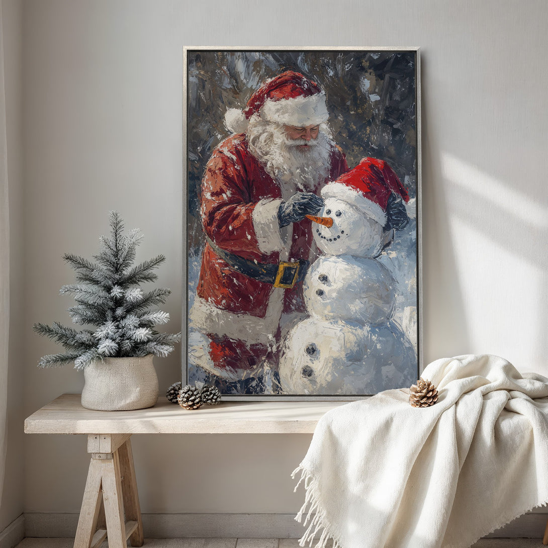 Framed Wall Art of Santa Claus building a snowman. Festive holiday art in a painterly style with red, white, and blue tones. Perfect Christmas decor.