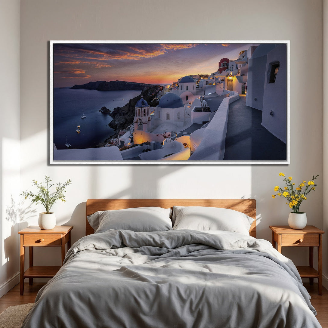 Framed Wall Art: Santorini sunset canvas print in bedroom. Coastal style art with warm sunset hues and blue accents. Bring the vacation vibes home!