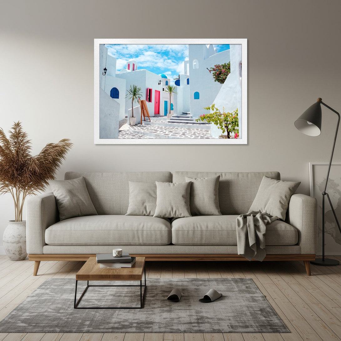 Framed Poster of a Santorini street scene. Coastal style with white buildings, blue accents, and pink doors. Perfect home decor.
