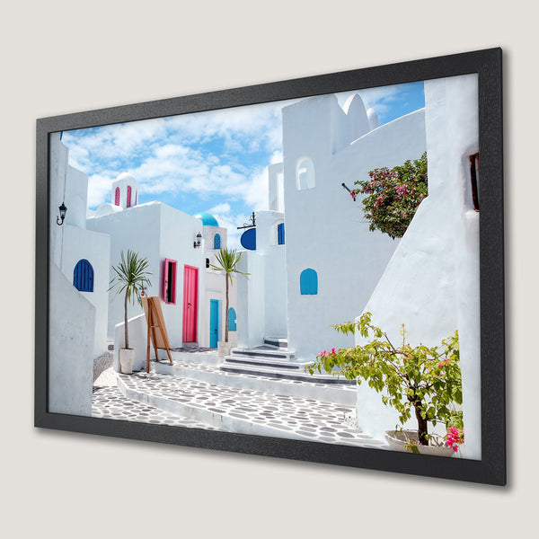Framed Poster of a Greek village with white buildings, blue accents, and a vibrant color palette. Perfect wall art!