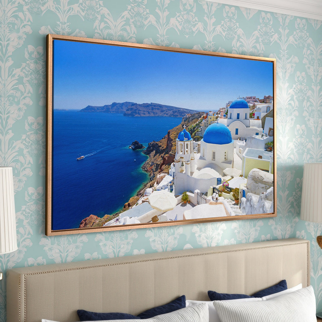 Framed Wall Art: Santorini Canvas Print. Captivating coastal scene with blue domes and sea. Perfect for adding a touch of Mediterranean charm to your home.