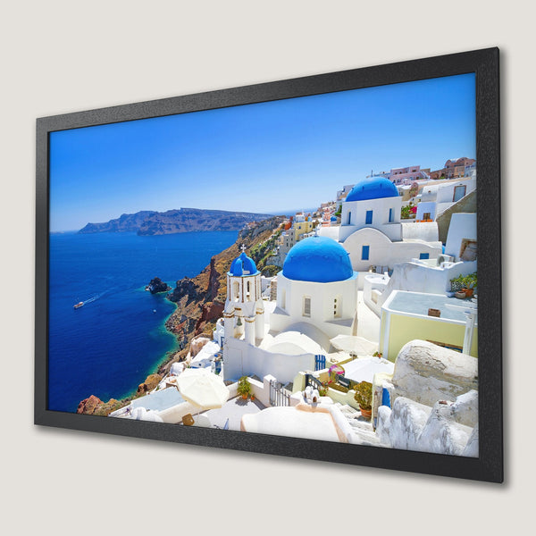 Framed Poster of Santorini, Greece. Captures iconic blue domes & white buildings against a vibrant blue sea. Mediterranean style, bright color palette.
