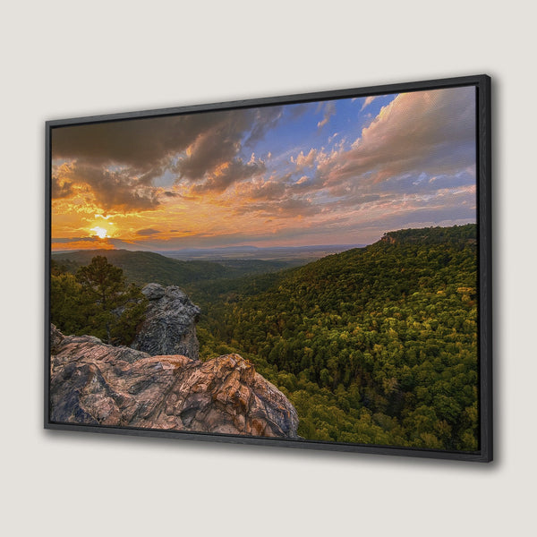 Framed Wall Art of a stunning sunset over a mountain landscape. Warm orange and gold hues dominate the sky, contrasting with lush green forest.