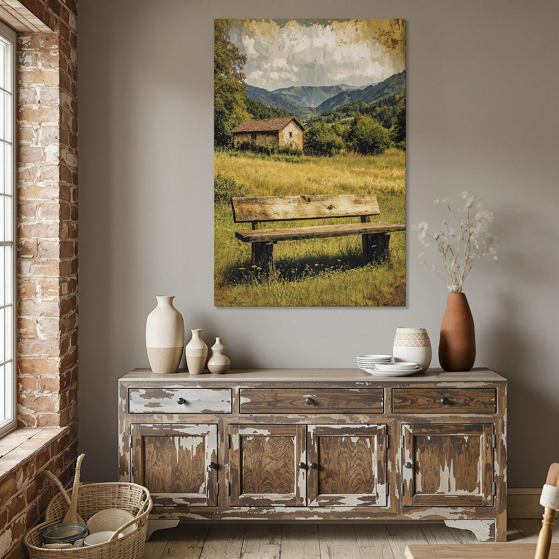 Framed Wall Art: Rustic landscape Canvas Print with a bench, cabin, and mountains. Warm, earthy tones create a cozy, inviting atmosphere for your home.