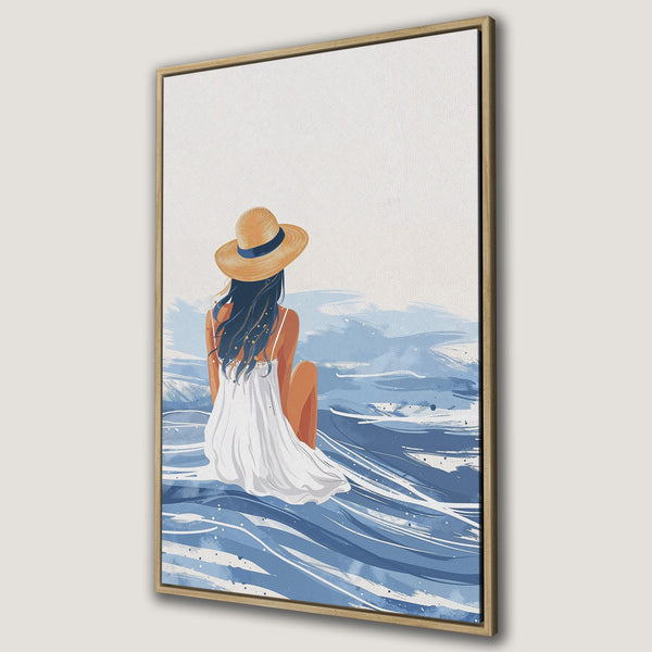 Framed Wall Art featuring a woman in a hat, facing the sea. Coastal-inspired art in blue and neutral tones. Perfect for adding a touch of serenity.