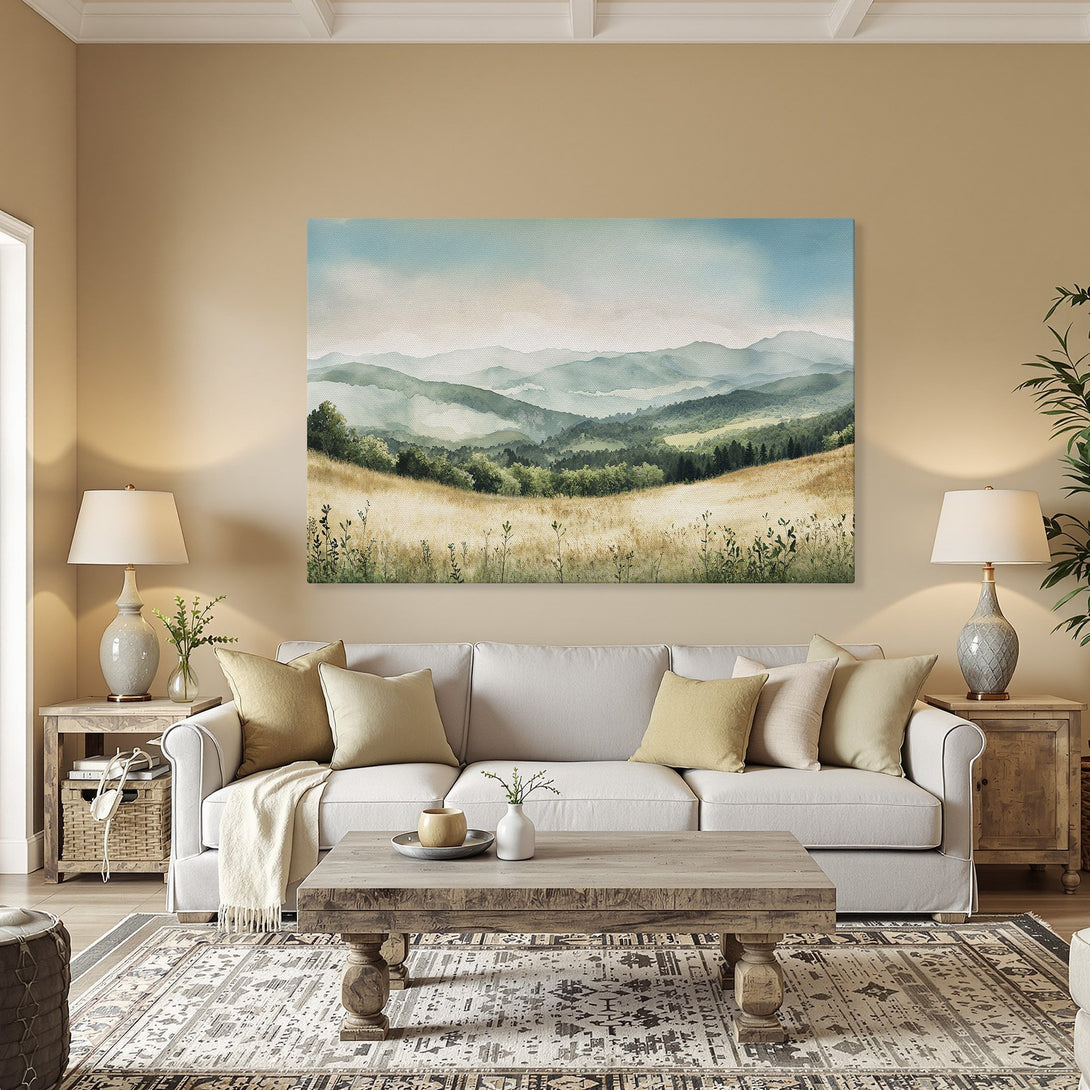 Framed Wall Art: Watercolor landscape canvas print in a warm interior. Features serene mountains & fields in blue, green, and gold tones.
