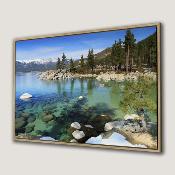 Framed Wall Art of a serene lake scene with clear turquoise water, rocks, and mountains. Nature-inspired art with blue and green hues.