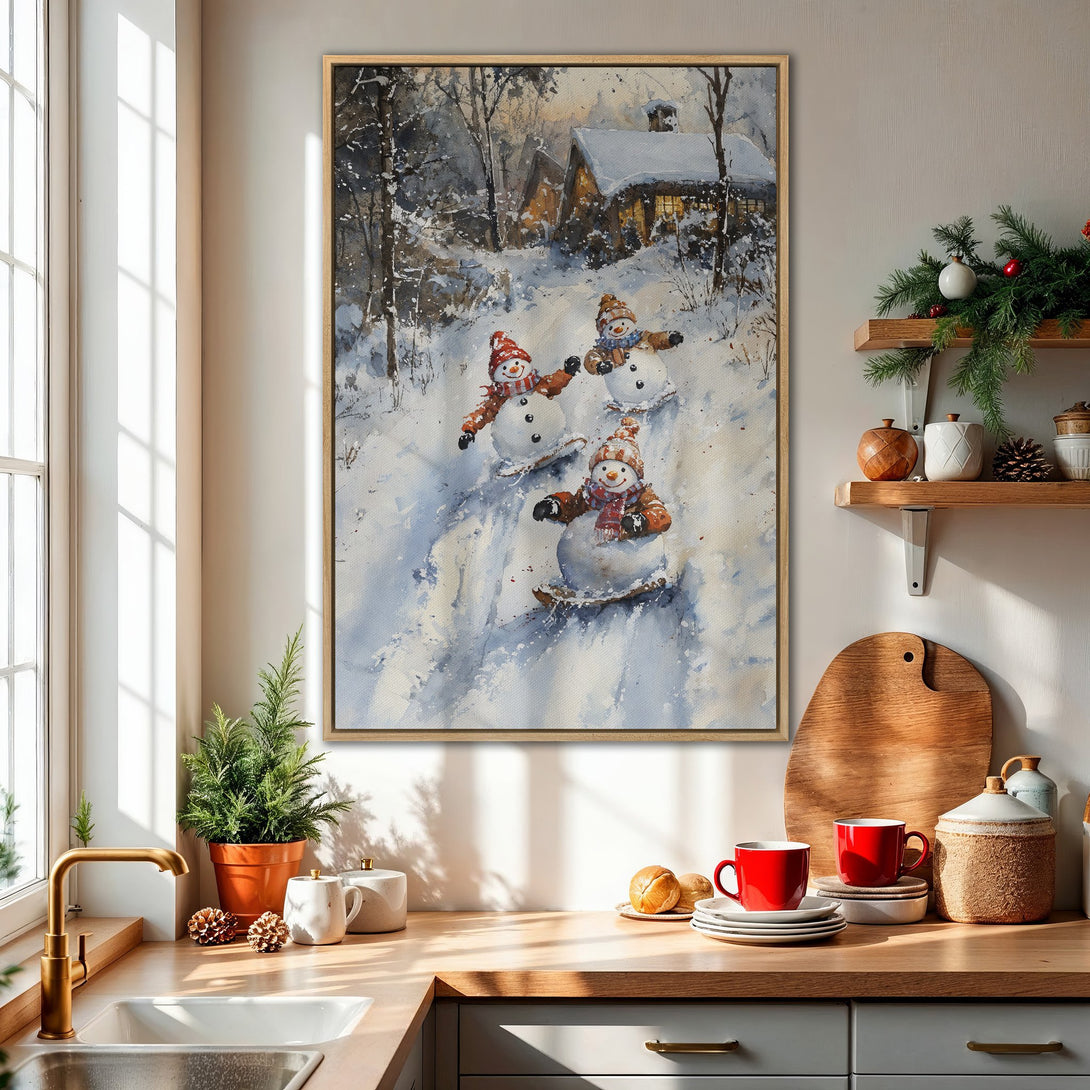 Framed Wall Art: Watercolor painting of snowmen sledding in a winter scene. Soft blues, grays, and warm reds create a cozy, festive feel. Perfect holiday decor!
