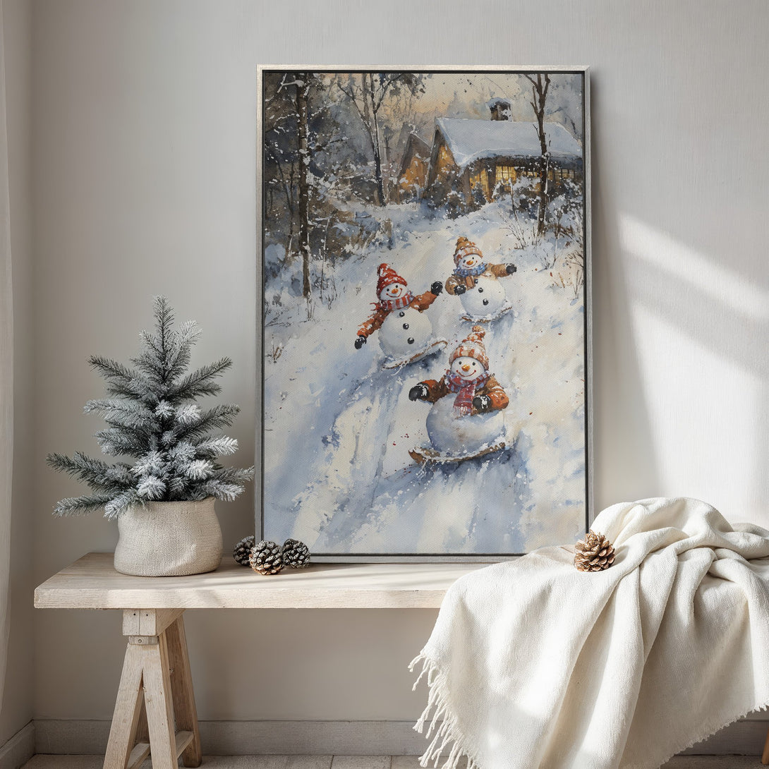 Framed Wall Art: Watercolor painting of snowmen skiing down a snowy hill, warm winter scene with a cozy cabin, in a neutral color palette.