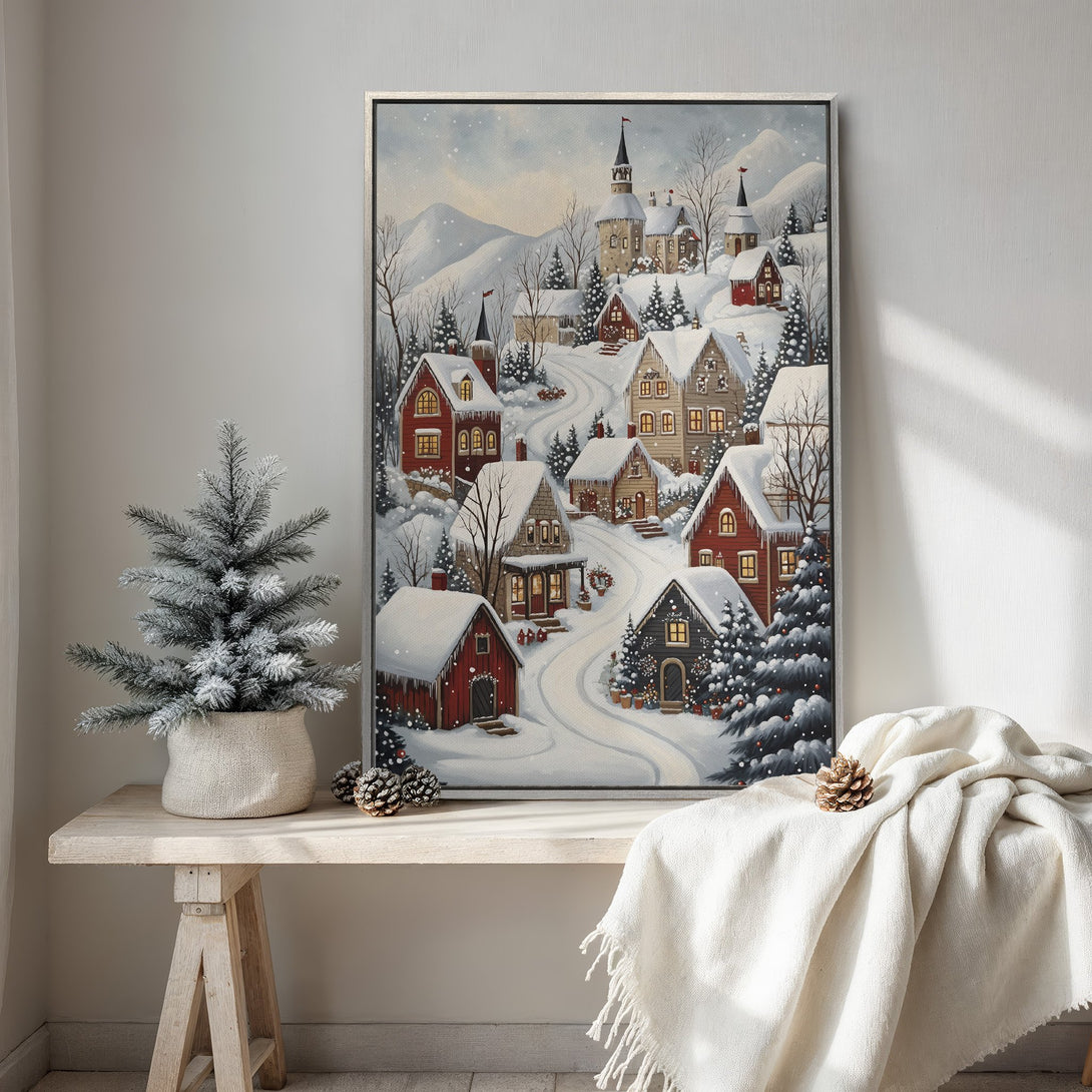 Framed Wall Art featuring a cozy winter village scene with snow-covered houses. Warm red and neutral tones create a charming, inviting aesthetic for your home decor.