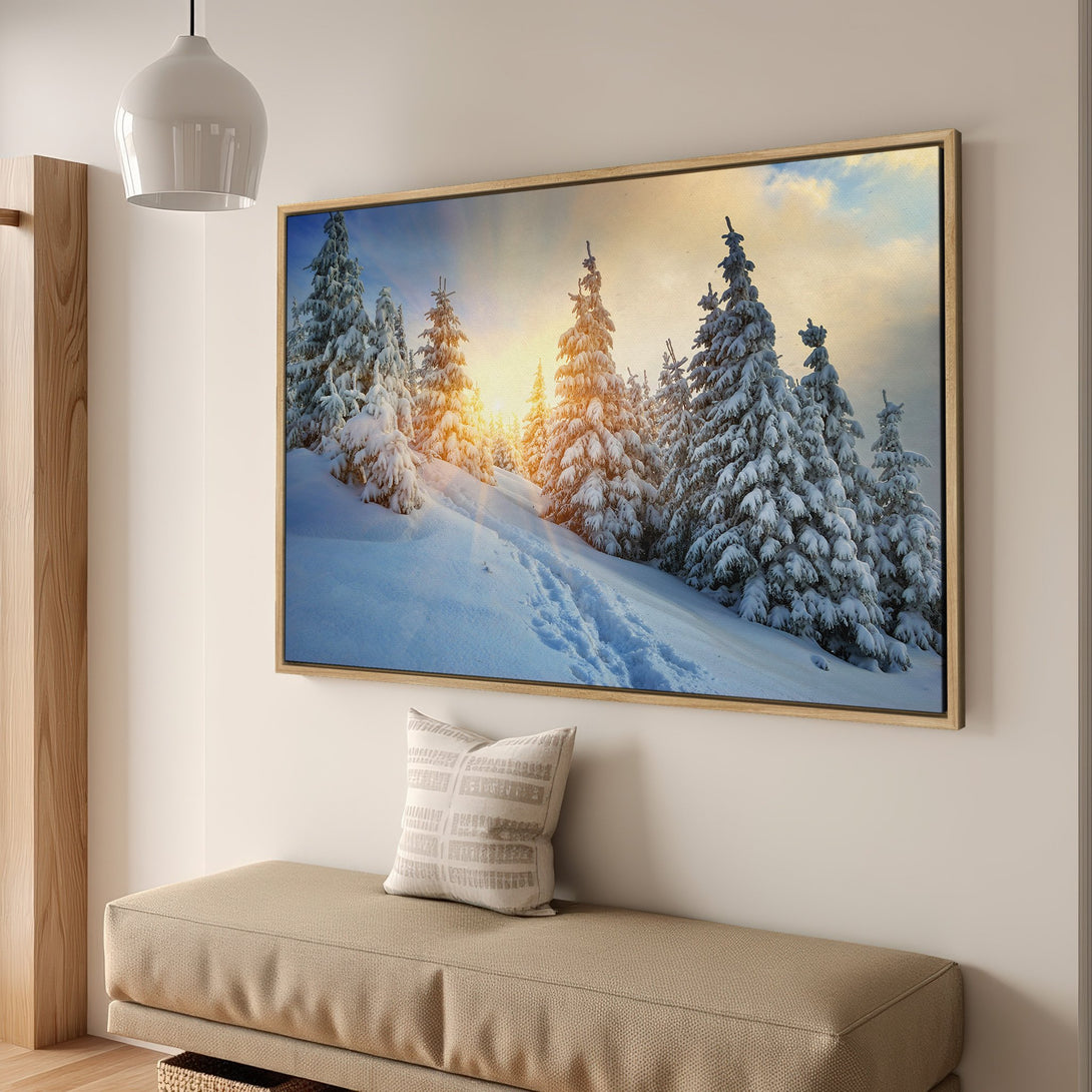 Framed Wall Art featuring a snowy winter landscape with pine trees and a warm color palette. Bring the beauty of nature into your home!