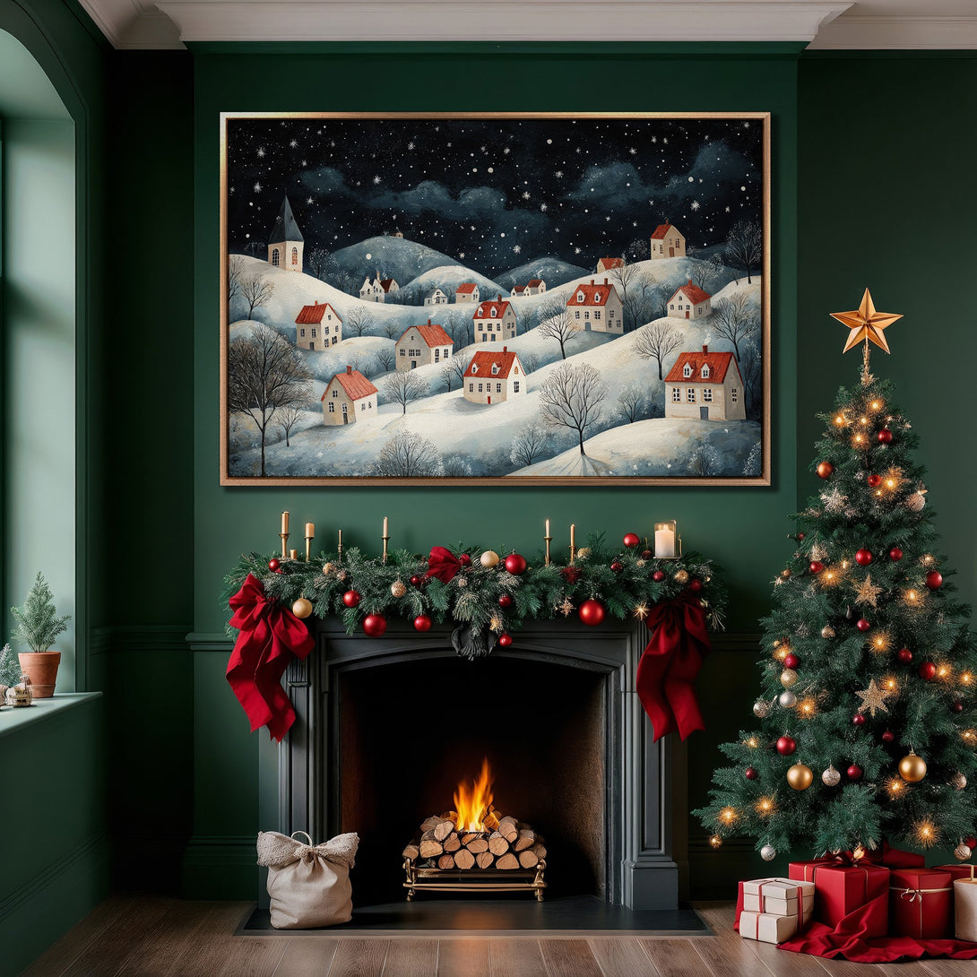 Framed Wall Art: Winter village scene Canvas Print in a cozy interior. Features a snowy landscape with red-roofed houses, a dark blue and white palette, and a gold frame.