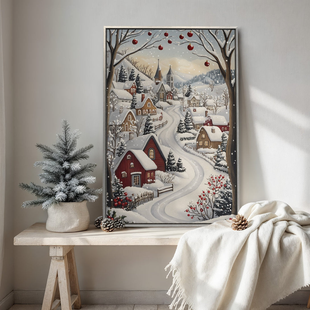 Framed Wall Art of a snowy village scene in a cozy, whimsical style. Features a wintery color palette with reds, whites, and browns. Perfect for holiday decor!