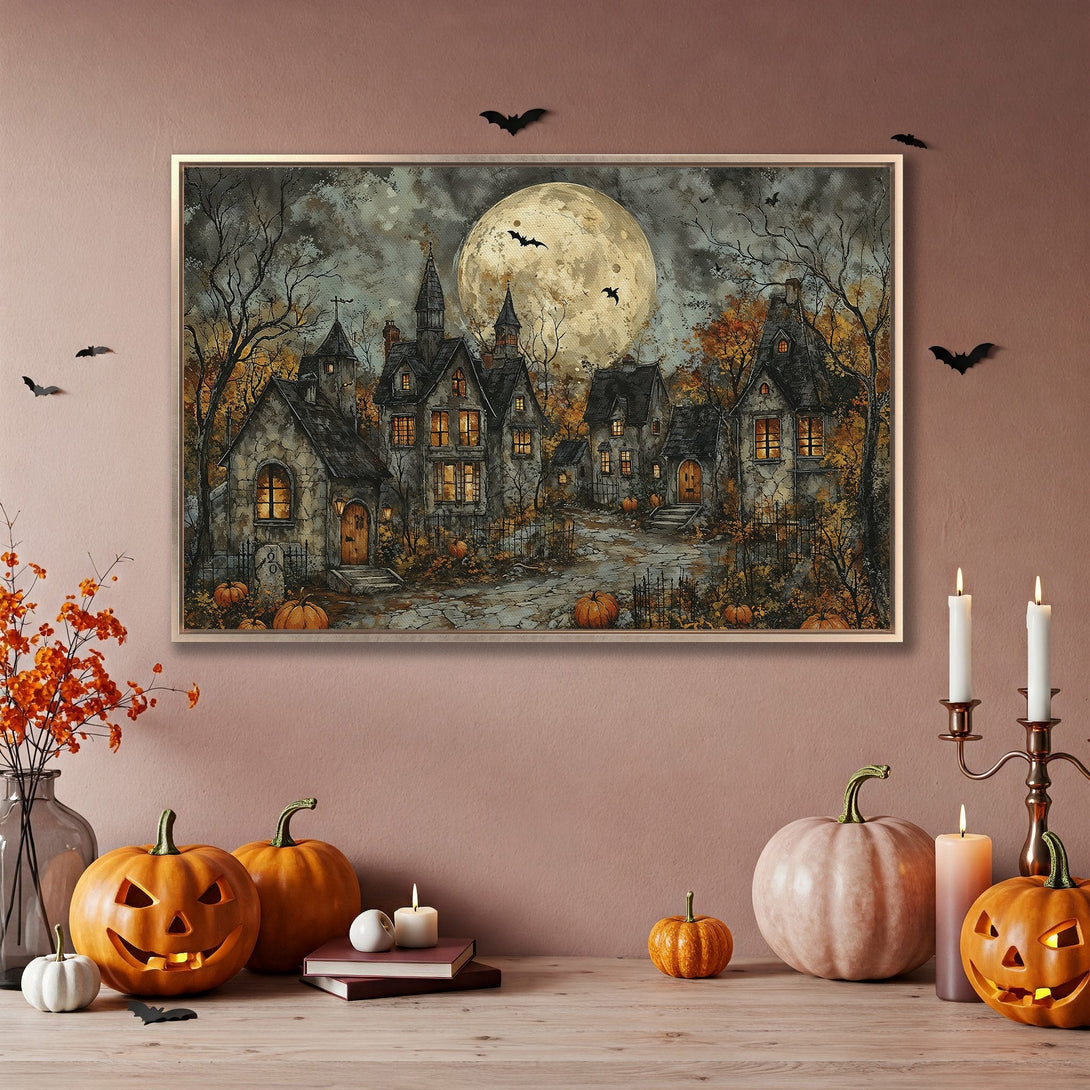 Framed Wall Art: Spooky Halloween scene canvas print featuring a full moon, haunted houses, and a warm autumnal color palette.