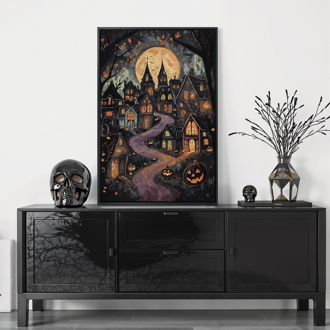 Framed Wall Art featuring a spooky Halloween village scene in a watercolor style with warm orange and cool purple tones. Perfect for seasonal decor!