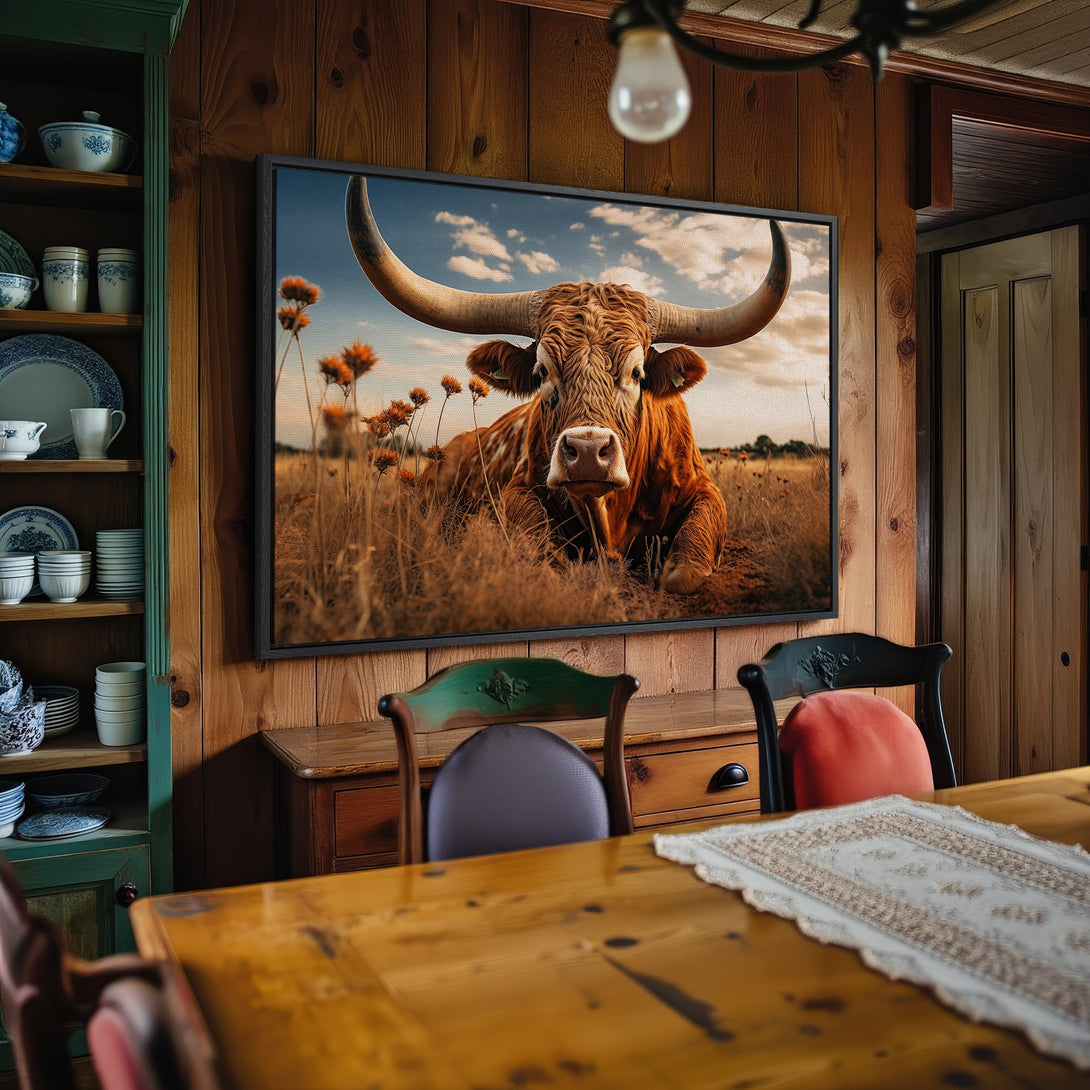 Framed Wall Art: Rustic canvas print of a longhorn in a field. Earthy tones of brown, orange, and blue. Perfect for farmhouse decor.