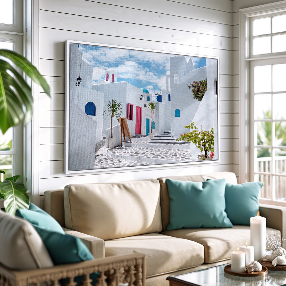 Framed Wall Art of a Greek village scene in white, blue, and pink. Coastal style Canvas Print adds a touch of Mediterranean charm to any room.