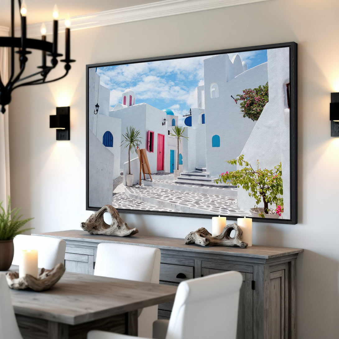 Framed Wall Art: Santorini street scene in white, blue, and pink. Coastal decor canvas print for a bright, airy interior design.