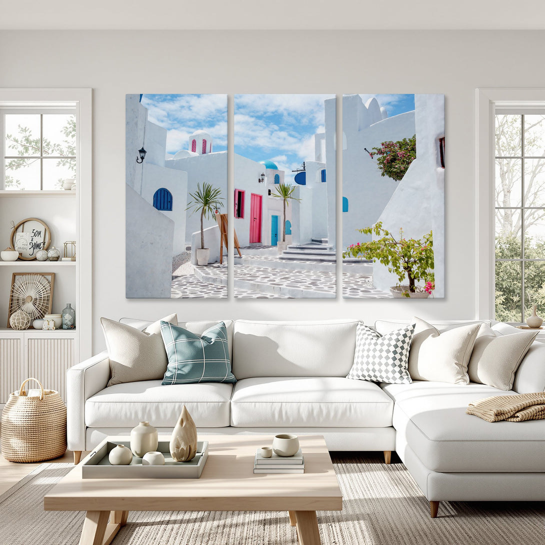 Canvas Print of a picturesque Greek village scene. White buildings with blue and pink accents against a bright blue sky. Mediterranean style wall art.