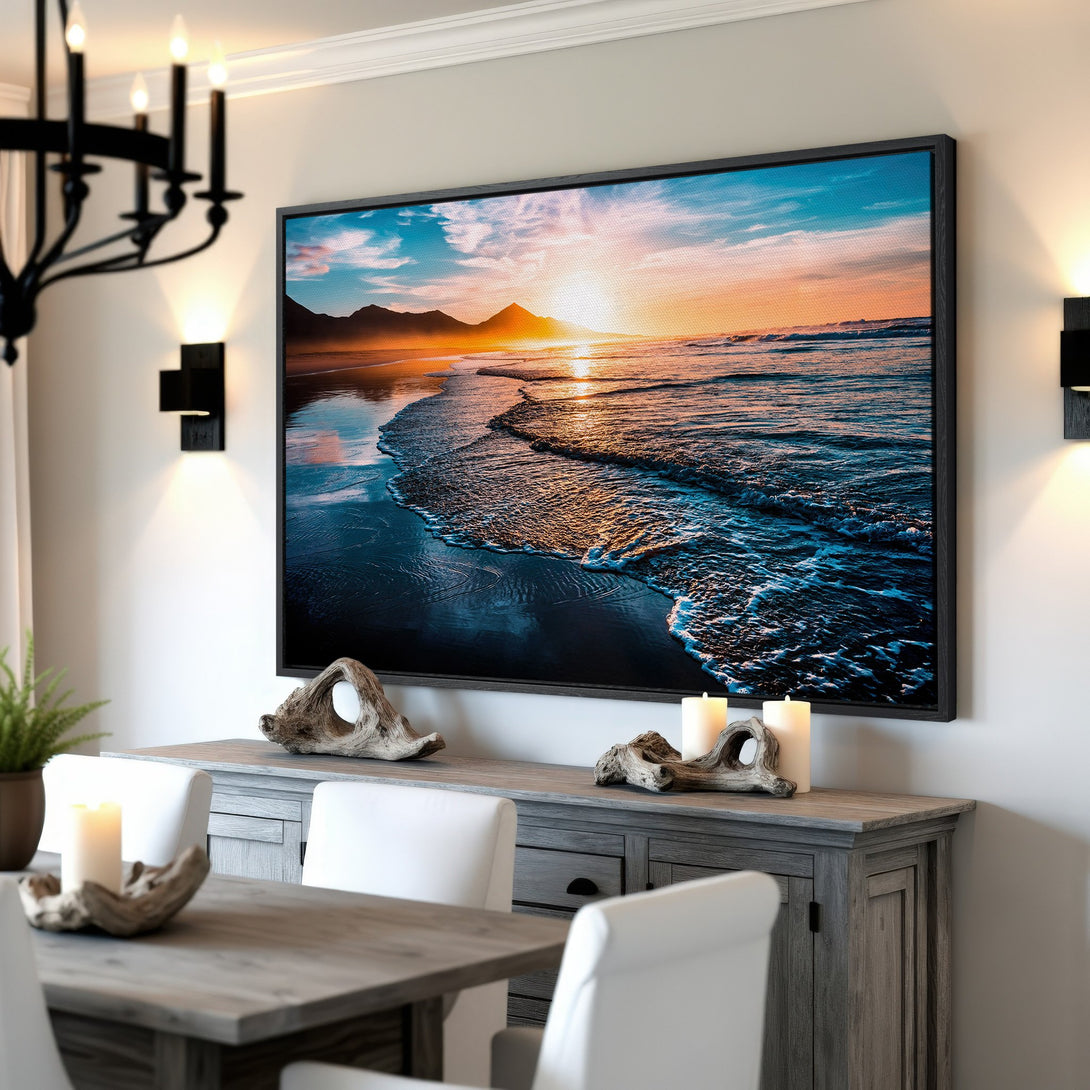 Framed Wall Art: Coastal sunset canvas print in a dining room. Features a serene beach scene with blue, orange, and teal hues. Perfect for modern home decor.