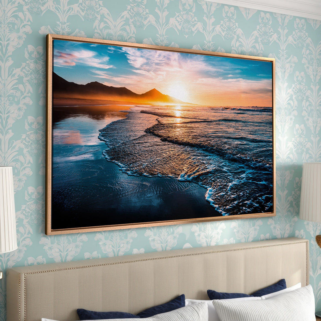 Framed Wall Art: Sunset over ocean canvas print in warm hues of orange, blue, and gold. Coastal landscape art for serene bedroom decor.