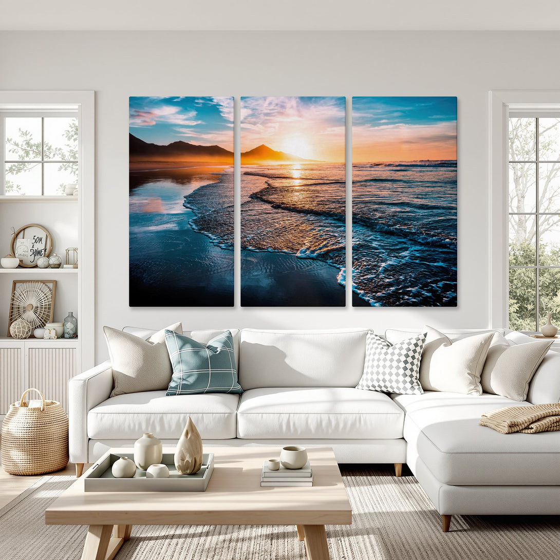 Canvas Print of a serene beach sunset in vibrant blues and oranges, displayed in a modern living room. Coastal wall art for home decor.