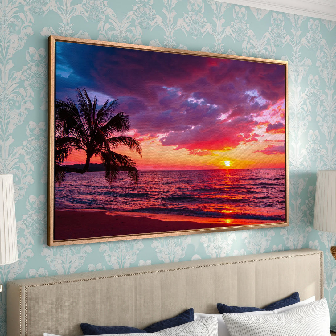 Framed Wall Art: Tropical sunset canvas print with palm tree silhouette. Vivid red, orange, and purple hues create a stunning coastal art piece for your home.