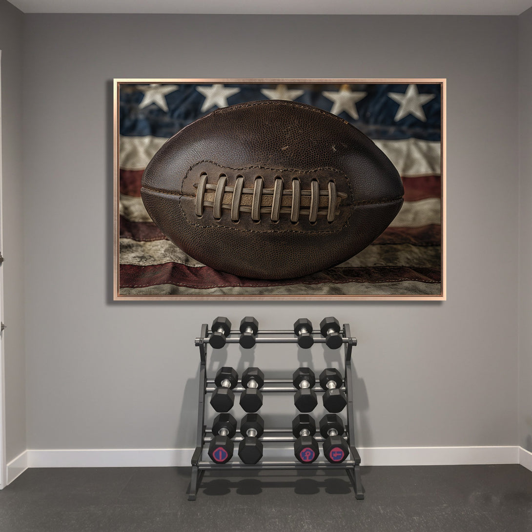 Framed Wall Art: Vintage football against American flag. Rustic, patriotic decor in brown, blue, and red tones. Perfect for a home gym or sports room.