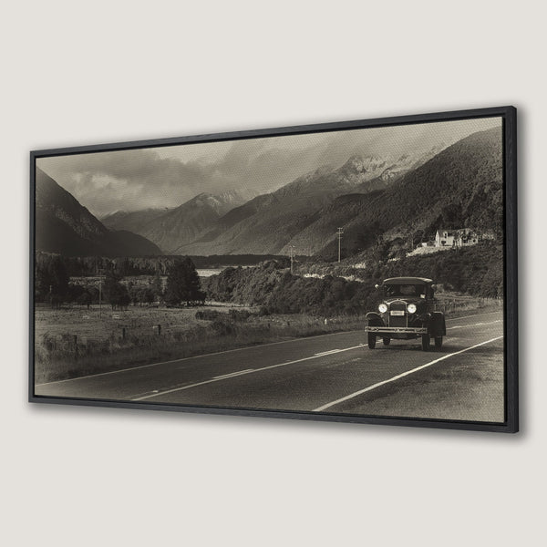 Framed Wall Art featuring a vintage car on a scenic road with mountains. Sepia-toned canvas print perfect for adding a touch of nostalgia.