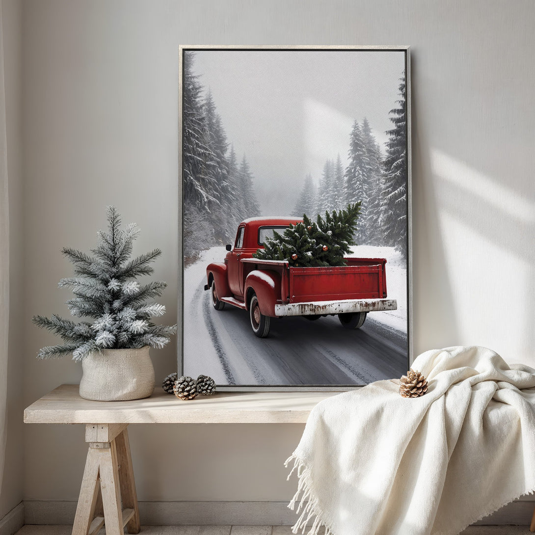 Framed Wall Art featuring a vintage red truck carrying a Christmas tree in a snowy forest scene. Rustic style with a red, white, and gray color palette.