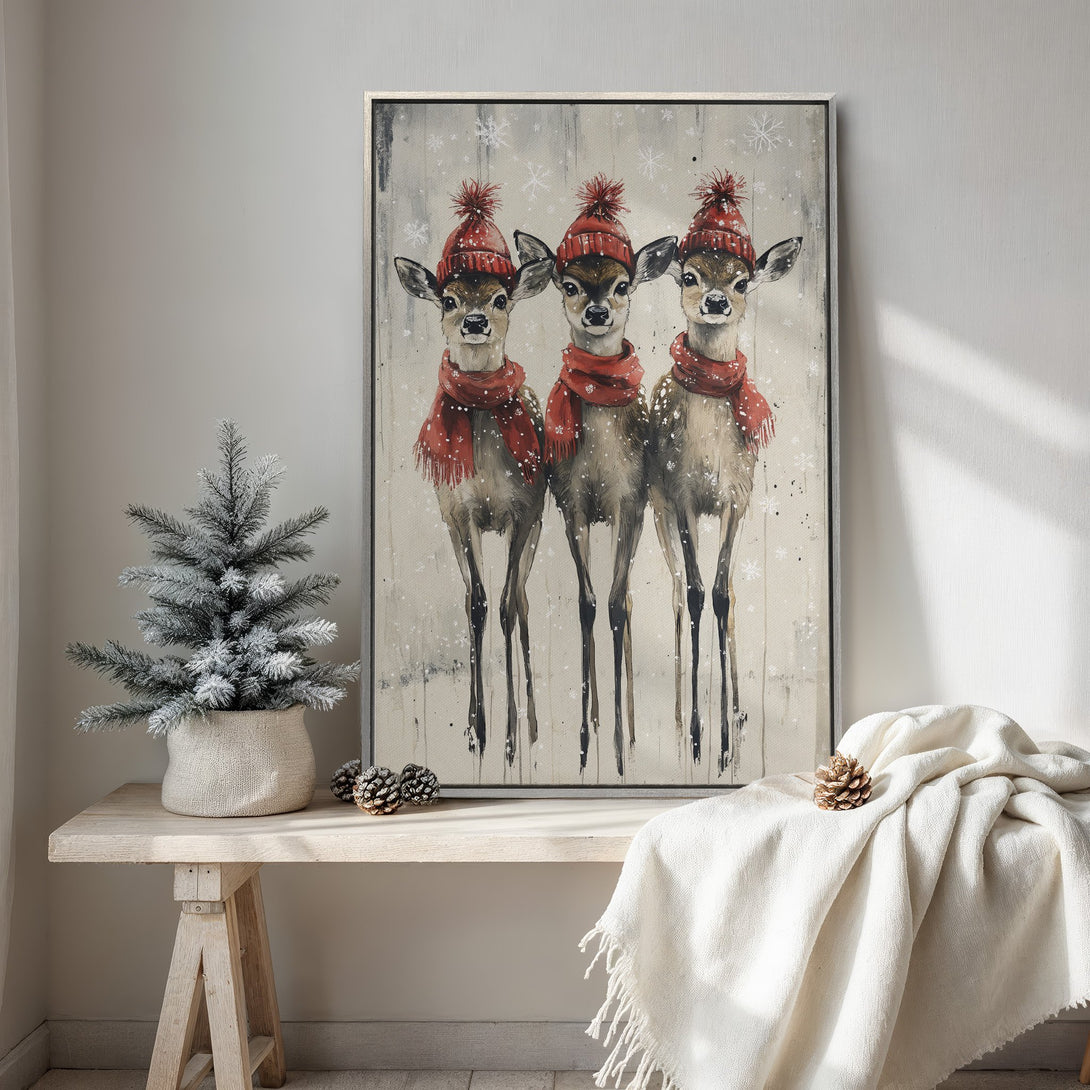 Framed Wall Art featuring three deer in red hats and scarves, winter scene. Rustic style with neutral and red color palette, perfect for holiday decor.