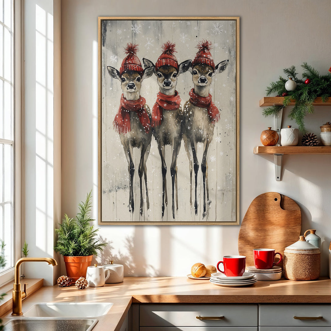 Framed Wall Art featuring three adorable deer in red hats and scarves. Winter-themed painting with a neutral and red color palette, perfect for holiday decor.