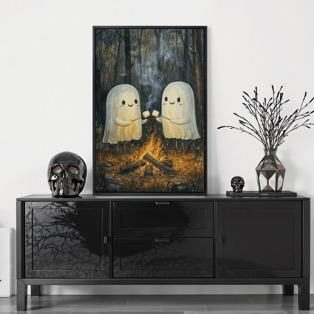 Framed Wall Art featuring two cute ghosts roasting marshmallows by a campfire in a forest. Warm, earthy tones create a cozy, whimsical feel. Perfect for Halloween decor!