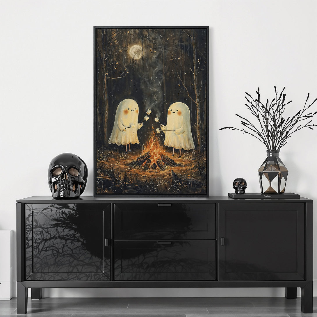 Framed Wall Art featuring two cute ghosts roasting marshmallows by a campfire. Warm, inviting color palette with a whimsical, illustrative style. Perfect for Halloween decor!