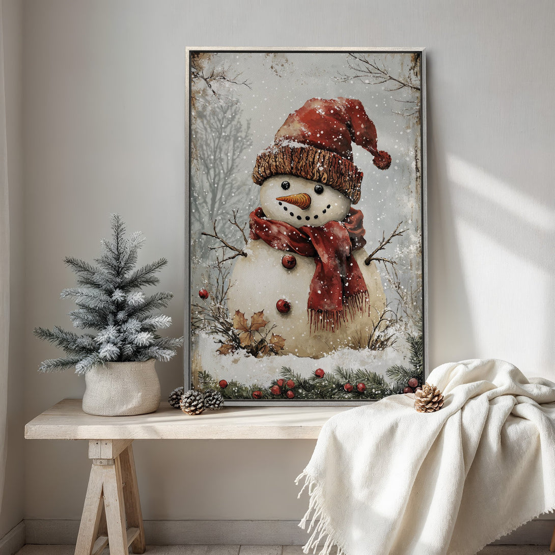 Framed Wall Art featuring a whimsical snowman in a cozy winter scene. Rustic style with a warm red and neutral color palette, perfect for holiday decor.