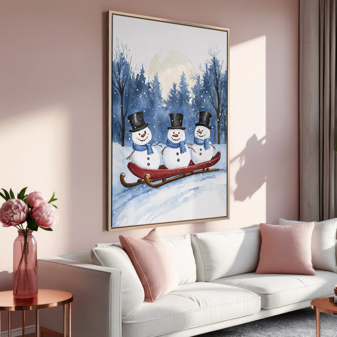 Framed Wall Art of watercolor snowmen on a sled, in a winter scene. Featuring a blue and white color palette, perfect for holiday decor.
