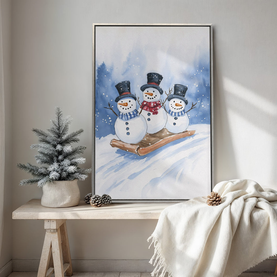 Framed Wall Art featuring watercolor snowmen on a sled. Winter-themed art in blue, white, and black color palette. Perfect holiday home decor.