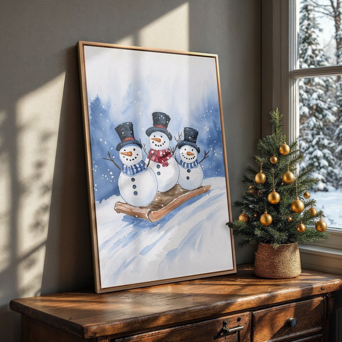 Framed Wall Art: Watercolor painting of snowmen on a sled, blue and white palette, perfect for winter decor. Cozy, whimsical art for your home!