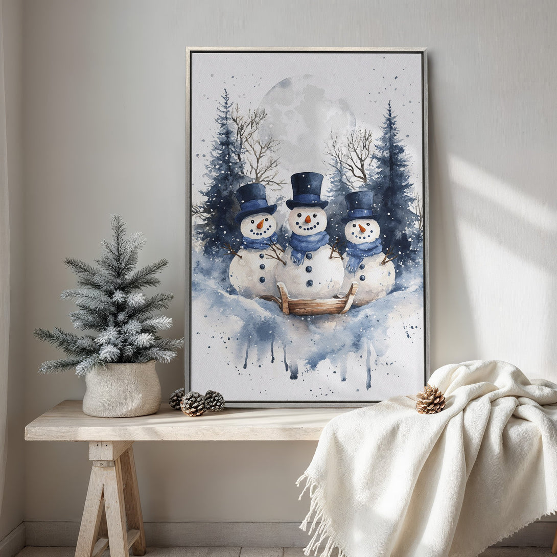 Framed Wall Art featuring a watercolor style winter scene with three snowmen in blue and white. Perfect for holiday decor.
