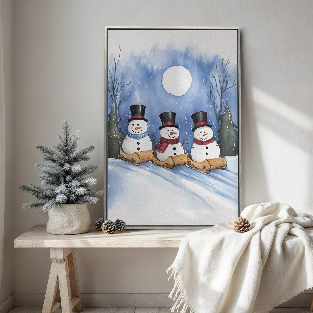 Framed Wall Art featuring watercolor snowmen in a winter scene. Blue and white color palette, perfect for holiday decor. Add cozy charm to your space!